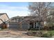 Charming exterior view of home featuring a three-car garage, gray siding, stone accents, and mature landscaping at 11785 W Belleview, Littleton, CO 80127