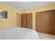 Cozy bedroom featuring a comfortable bed with yellow walls and wood closet doors at 1650 Bedivere Cir, Lafayette, CO 80026
