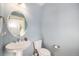 Powder room with blue walls, pedestal sink, toilet and round mirror at 21383 E Smoky Hill Rd, Centennial, CO 80015