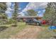 Attractive home exterior with a dark SUV and red car parked outside, complemented by mature trees and greenery at 7715 Rafter Rd, Franktown, CO 80116