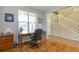 Bright home office with hardwood floors, a wooden desk, and staircase in view through doorway at 1017 Mircos St, Erie, CO 80516