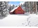 This charming red barn surrounded by snow-covered evergreens is the perfect mountain retreat at 8699 Blue Creek Rd, Evergreen, CO 80439
