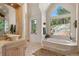 Bright bathroom features a soaking tub with scenic views from large geometric and standard windows at 8699 Blue Creek Rd, Evergreen, CO 80439