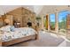 Bright bedroom with stone fireplace and doors leading to private deck at 8699 Blue Creek Rd, Evergreen, CO 80439