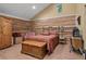 This cozy bedroom boasts unique log walls, wood floors, a vintage wardrobe, and plenty of natural light at 8699 Blue Creek Rd, Evergreen, CO 80439