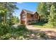 Beautiful log cabin exterior with stone base, complemented by a landscaped yard, driveway, and natural surroundings at 8699 Blue Creek Rd, Evergreen, CO 80439