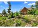 Exterior of log cabin home with native landscaping and stone walkway leading to the front door at 8699 Blue Creek Rd, Evergreen, CO 80439