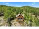 Aerial view of a log cabin home surrounded by trees with a stone walkway to the front door at 8699 Blue Creek Rd, Evergreen, CO 80439