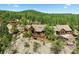 A sprawling log home sits atop a rocky ridge, surrounded by lush forest with an additional small log cabin nearby at 8699 Blue Creek Rd, Evergreen, CO 80439