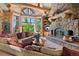 Cozy living room with a stone fireplace, exposed wooden beams, and large windows offering scenic views of the outdoors at 8699 Blue Creek Rd, Evergreen, CO 80439