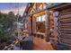 Inviting log home porch with string lights and views of the surrounding landscape at dusk at 8699 Blue Creek Rd, Evergreen, CO 80439