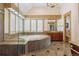 An elegant bathroom with a jacuzzi tub, stone surround, decorative lighting, and wooden cabinets at 81 Falcon Hills Dr, Highlands Ranch, CO 80126