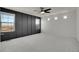 Expansive primary bedroom with a striking black accent wall, ceiling fan, and abundant natural light from multiple windows at 10124 Xanadu St, Commerce City, CO 80022