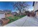Fenced backyard with mature tree, play structure, storage shed, and raised garden at 6550 W 74Th Pl, Arvada, CO 80003
