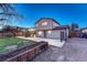 Back exterior of home with deck, stone patio, garden beds, and lush green lawn at 6550 W 74Th Pl, Arvada, CO 80003