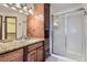 Bathroom featuring granite counters, wood cabinets, a shower with glass doors, and modern lighting at 11042 Blackwolf Ln, Parker, CO 80138