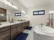 Bright bathroom with double vanity, a soaking tub, and modern fixtures, all under soft lighting at 5492 Woodroot Pt, Castle Rock, CO 80104