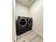 Modern laundry room with front loading washer and dryer set on wood-look floors at 5492 Woodroot Pt, Castle Rock, CO 80104