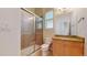 Bright bathroom features a glass enclosed shower and granite topped vanity with natural wood cabinet at 6187 Reed Way, Arvada, CO 80003