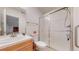 Bathroom features glass enclosed shower and natural wood cabinet sink with tile counter and backsplash at 6187 Reed Way, Arvada, CO 80003