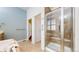 Primary bathroom features shower stall with glass door, natural wood cabinets and large soaking tub at 6187 Reed Way, Arvada, CO 80003