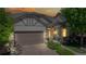 Dusk view of charming home with a two-car garage, covered porch, and manicured landscaping  at 6187 Reed Way, Arvada, CO 80003