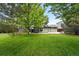 View of home's backyard with large grassy lawn, deck, and mature trees at 9315 Field Ln, Westminster, CO 80021