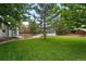 Scenic shot of the backyard featuring storage sheds, lush green grass, and mature trees at 9315 Field Ln, Westminster, CO 80021