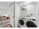 Bright laundry room with modern washer and dryer, convenient storage shelves, and a glimpse of a cozy living space at 9315 Field Ln, Westminster, CO 80021