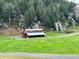 Barn with a metal roof stands amidst green fields, complemented by surrounding trees and serene countryside at 60 N County Highway 67, Sedalia, CO 80135