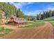Rustic barn with a metal roof and unique design set in a natural landscape with a dirt driveway at 60 N County Highway 67, Sedalia, CO 80135