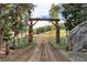 Rustic entrance to Bear Creek Ranch with wooden archway, wheel accents, and a dirt road leading into the property at 60 N County Highway 67, Sedalia, CO 80135