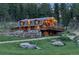 A view of the log cabin with lots of windows and decks and a natural stone retaining wall at 60 N County Highway 67, Sedalia, CO 80135