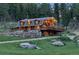 Charming log home featuring a stone foundation, covered porch, and a sprawling deck surrounded by mature trees at 60 N County Highway 67, Sedalia, CO 80135