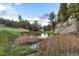 Scenic view of a barn reflecting in a pond surrounded by lush foliage and large boulders at 60 N County Highway 67, Sedalia, CO 80135