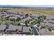 Wide aerial shot showcases a residential area with neatly aligned homes, landscaped roads, and mountain views in the distance at 4718 Raven Run, Broomfield, CO 80023