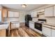 Bright kitchen featuring sleek appliances, white cabinets with wood trim, and stylish countertops with wood flooring at 5120 Perth St, Denver, CO 80249