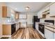 Well-lit kitchen featuring modern appliances, white cabinets with wood trim, and sleek countertops and wood flooring at 5120 Perth St, Denver, CO 80249