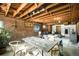 Open basement with a rustic dining table, exposed brick, and a cozy living space at 1256 N Emerson St, Denver, CO 80218