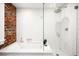 Updated bathroom with white subway tile, exposed brick and glass shower at 1256 N Emerson St, Denver, CO 80218