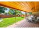 Covered backyard patio with wood ceiling features an outdoor table, grill, and seating at 3925 Newland St, Wheat Ridge, CO 80033