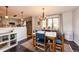 Cozy dining area featuring a wooden table with blue chairs, a large window, and a view of the kitchen at 4645 W Temple Pl, Denver, CO 80236