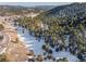 Gorgeous aerial view of a snow-covered landscape with dense evergreen forests and rolling hills in the background at 1053 Red Moon Rd, Evergreen, CO 80439