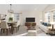 Virtually staged living room with a white couch and dining table at 9488 Brook Ln, Lone Tree, CO 80124