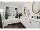 Bright bathroom with dual sinks, white cabinets, wood look floors, a soaking tub, and plants at 10938 Mcclellan Rd, Parker, CO 80134