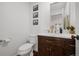 Elegant powder room features a wood vanity with a marble countertop and gold hardware, with three paintings on the wall at 10938 Mcclellan Rd, Parker, CO 80134