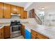 Practical kitchen with wooden cabinets, tile countertops, and stainless steel oven, and breakfast bar at 21052 E 45Th Ave, Denver, CO 80249
