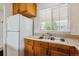 Kitchen with a double stainless steel sink under the window and wooden cabinets, next to a white refrigerator at 21052 E 45Th Ave, Denver, CO 80249