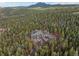 Aerial view of estate surrounded by dense forest, featuring a circular driveway and beautiful stone and stucco exterior at 11406 Conifer Ridge Dr, Conifer, CO 80433