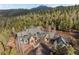 Stunning mountain home with stone and wood exterior, surrounded by lush forest and a mountain backdrop at 11406 Conifer Ridge Dr, Conifer, CO 80433